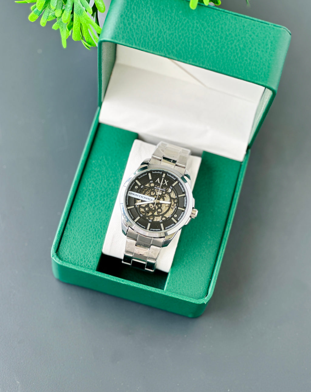 Silver watch in a green box on a gray background