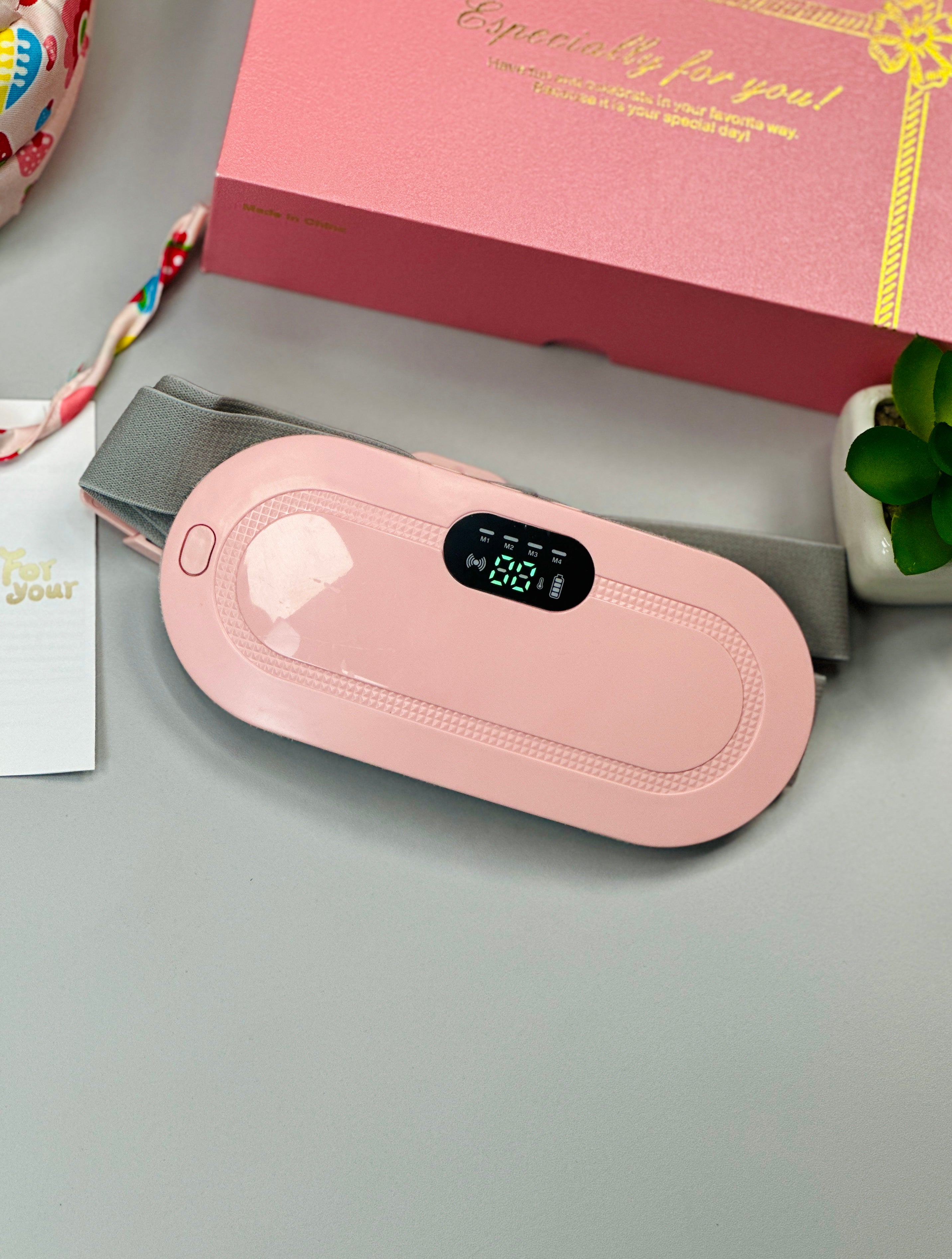 Pink electronic device on a gray surface with a gift box in the background